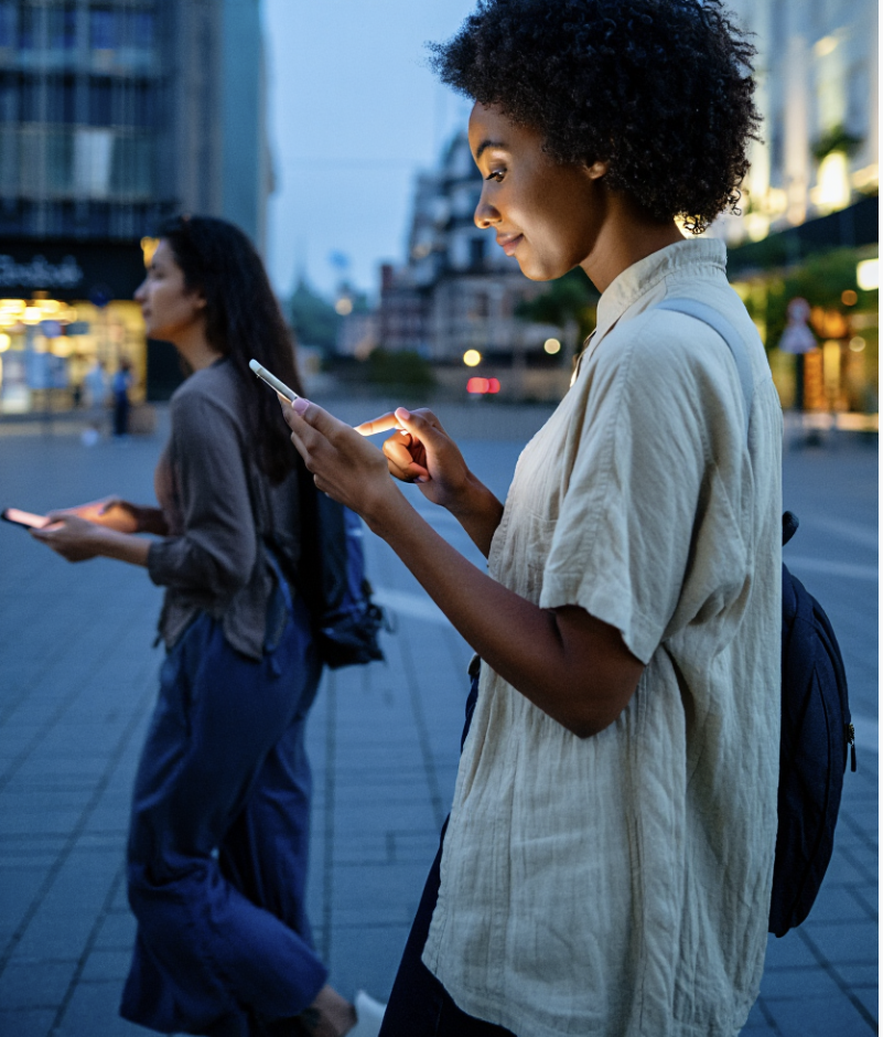 Deux femmes marchant en ville le soir avec leurs smartphones